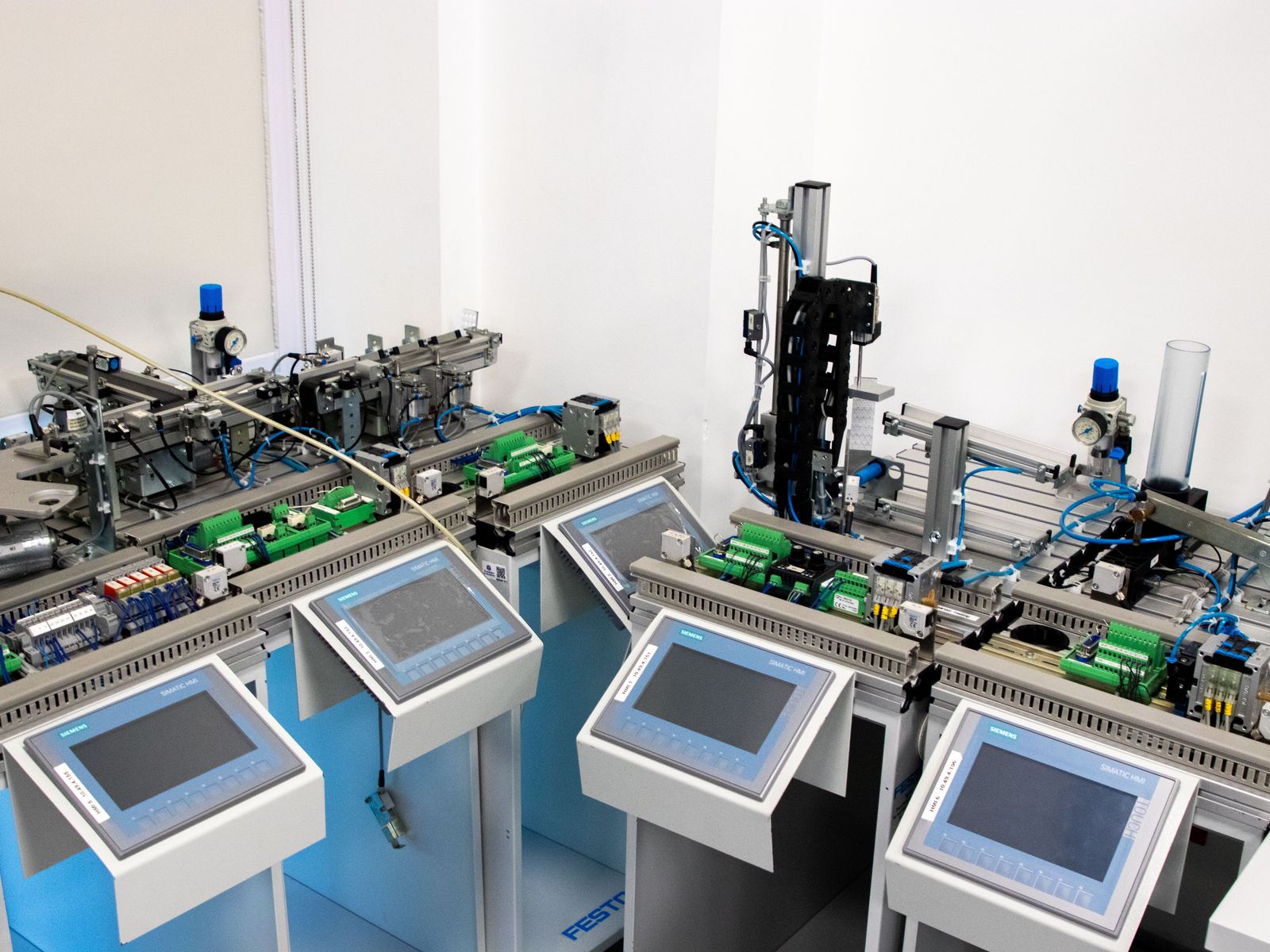 Row of automated test stations with touch panels.