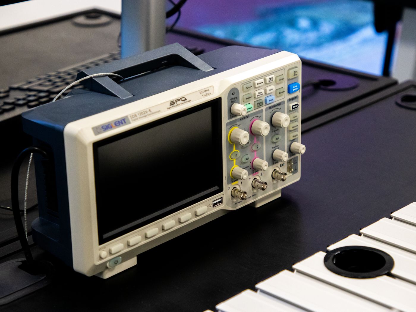 Oscilloscope and measurement equipment on an electronics workbench.