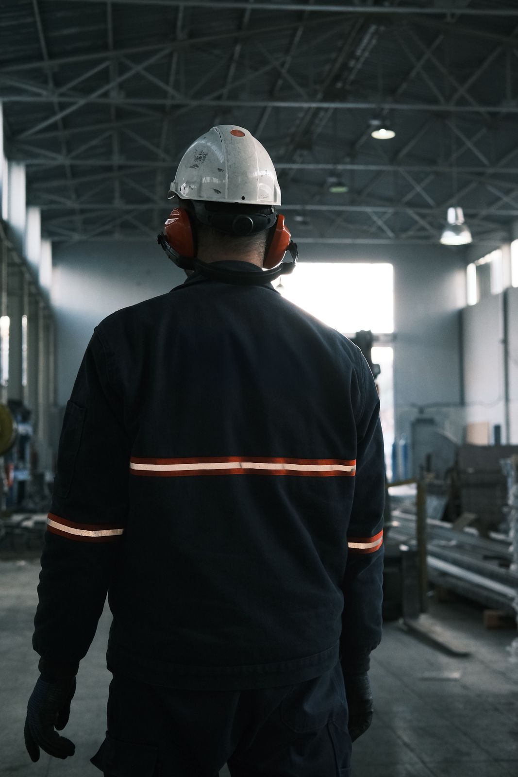 Operator in a helmet and safety gear on a factory floor.