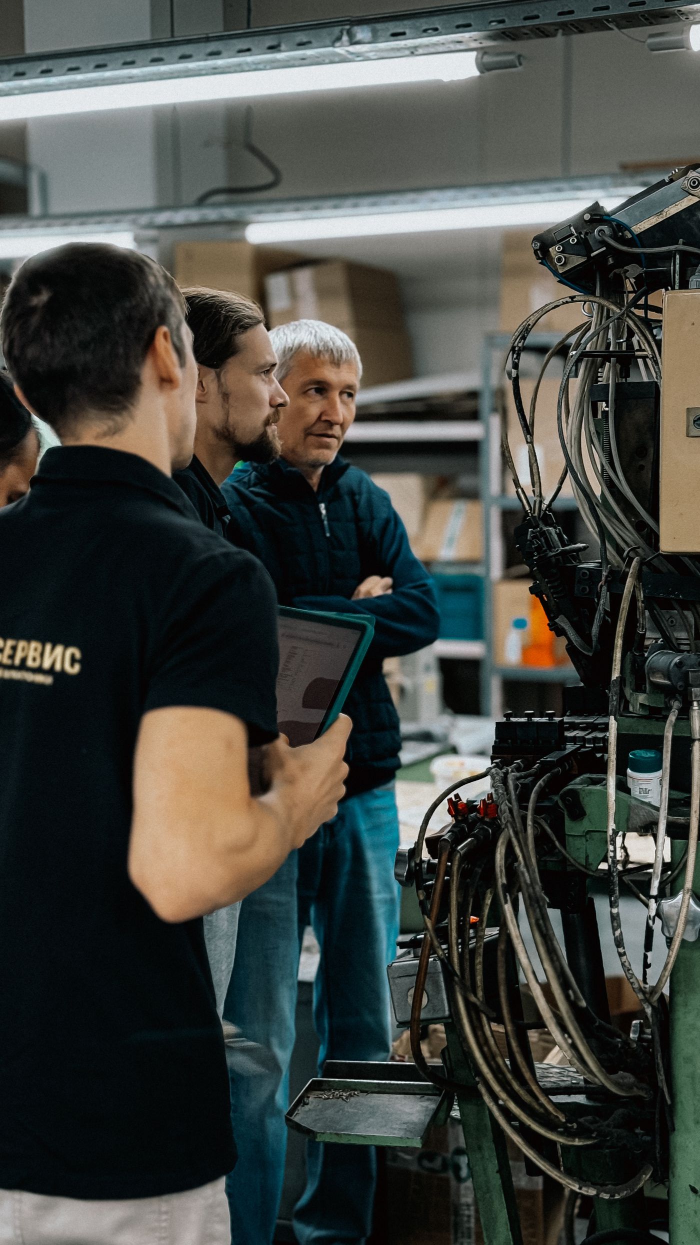 Engineers discussing work beside an open machine cabinet.