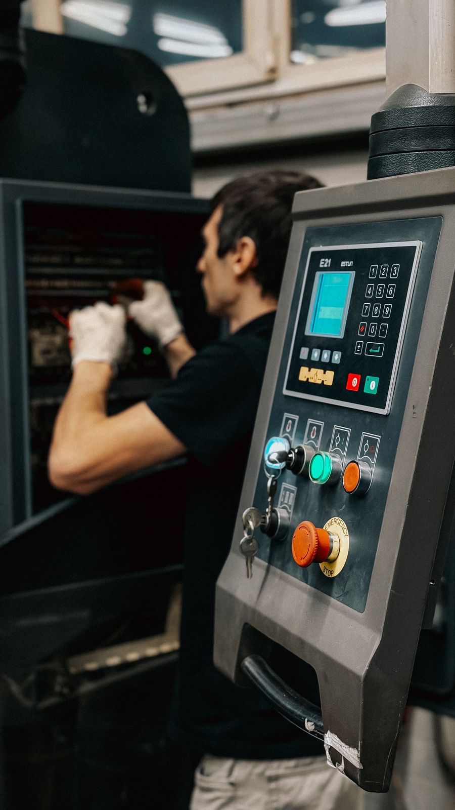 Technician working at a machine with its control panel.