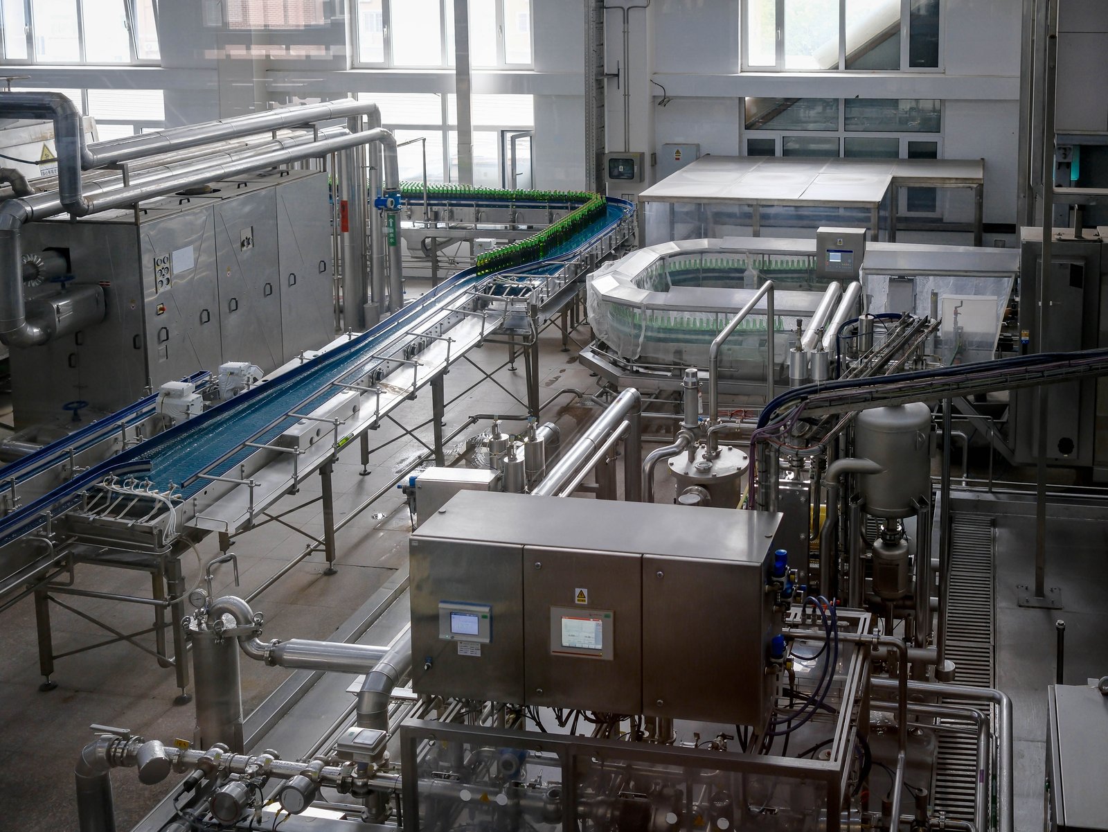 Modern automated filling line with conveyors and control cabinets.