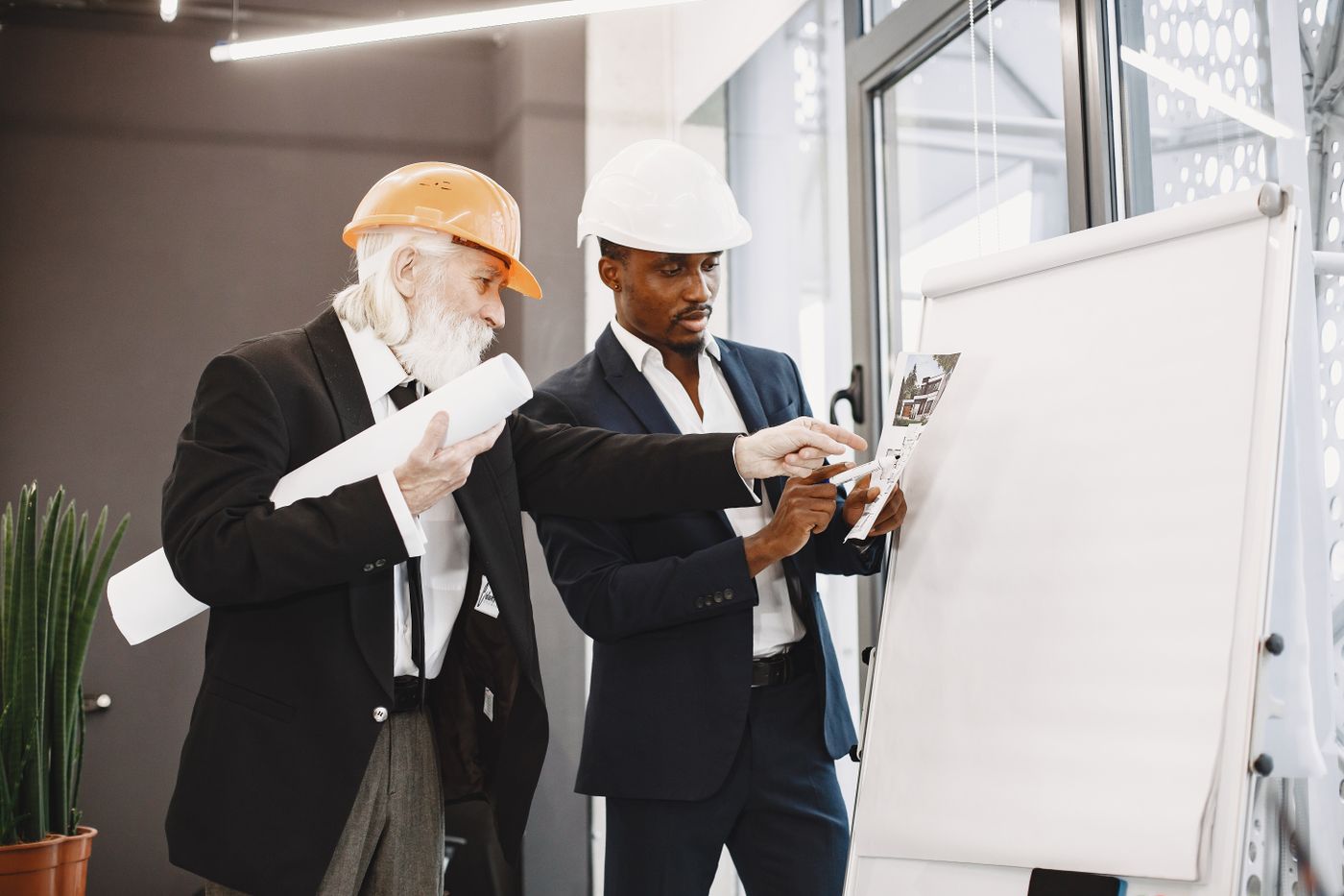 Two engineering colleagues reviewing a plan at a whiteboard.