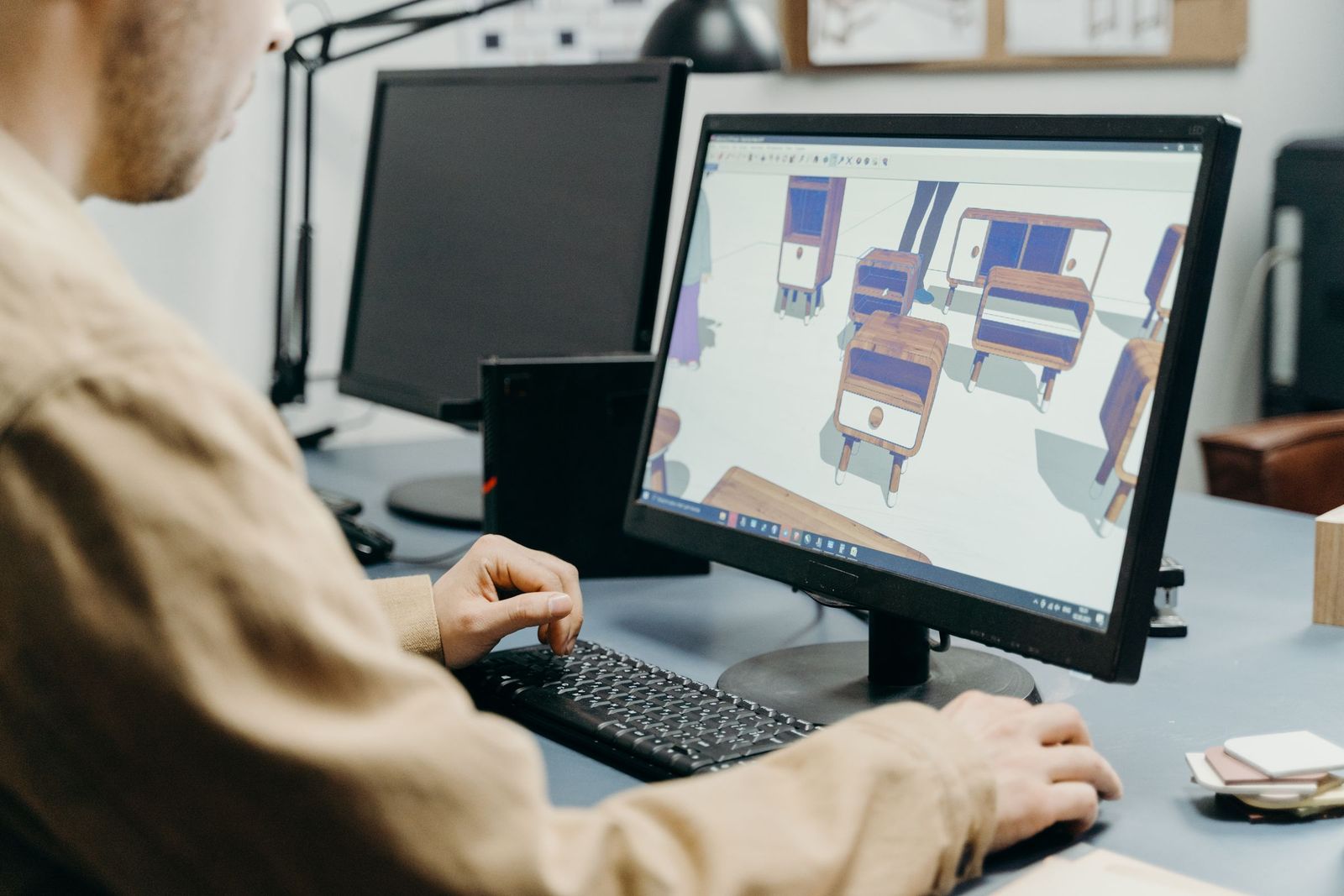 Engineer building a 3D layout model on a desktop monitor.
