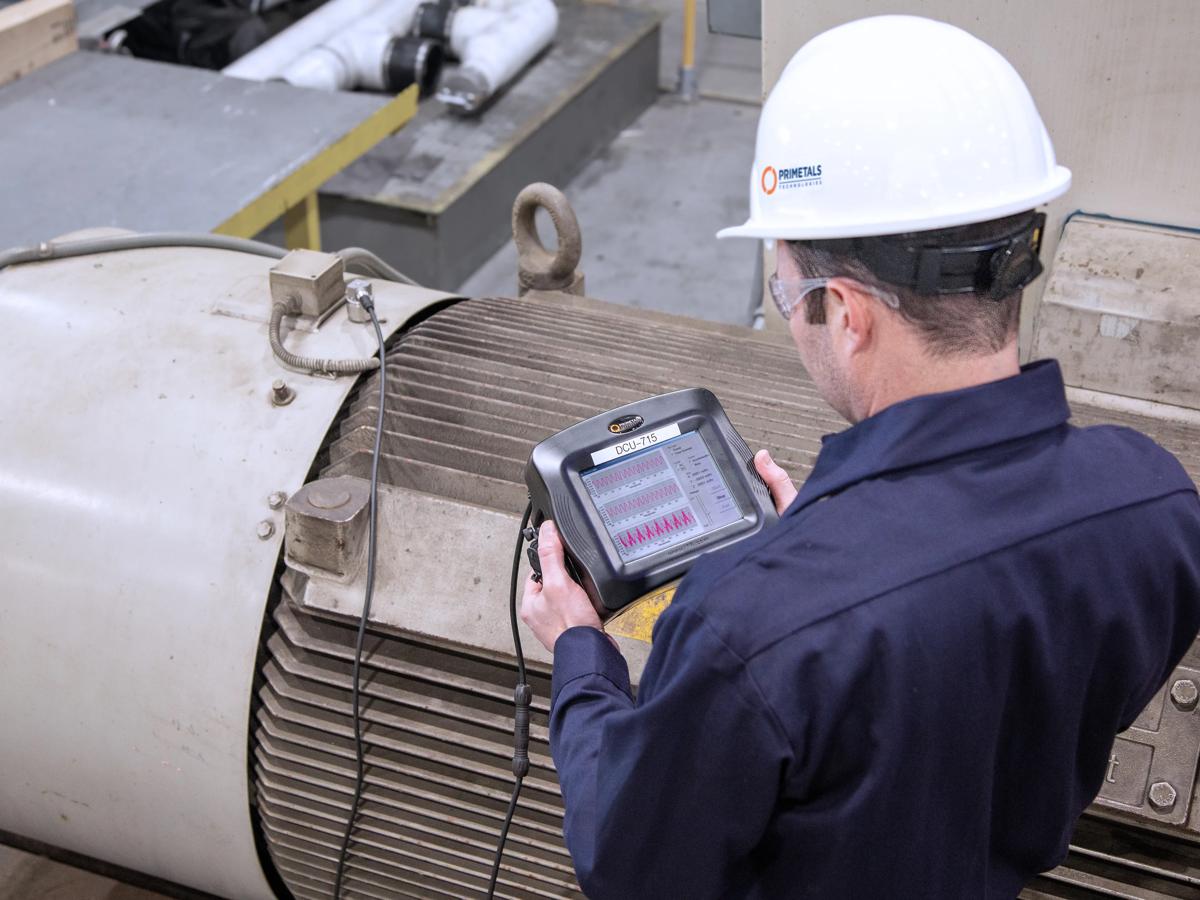 Engineer measuring motor vibration with a handheld analyser.